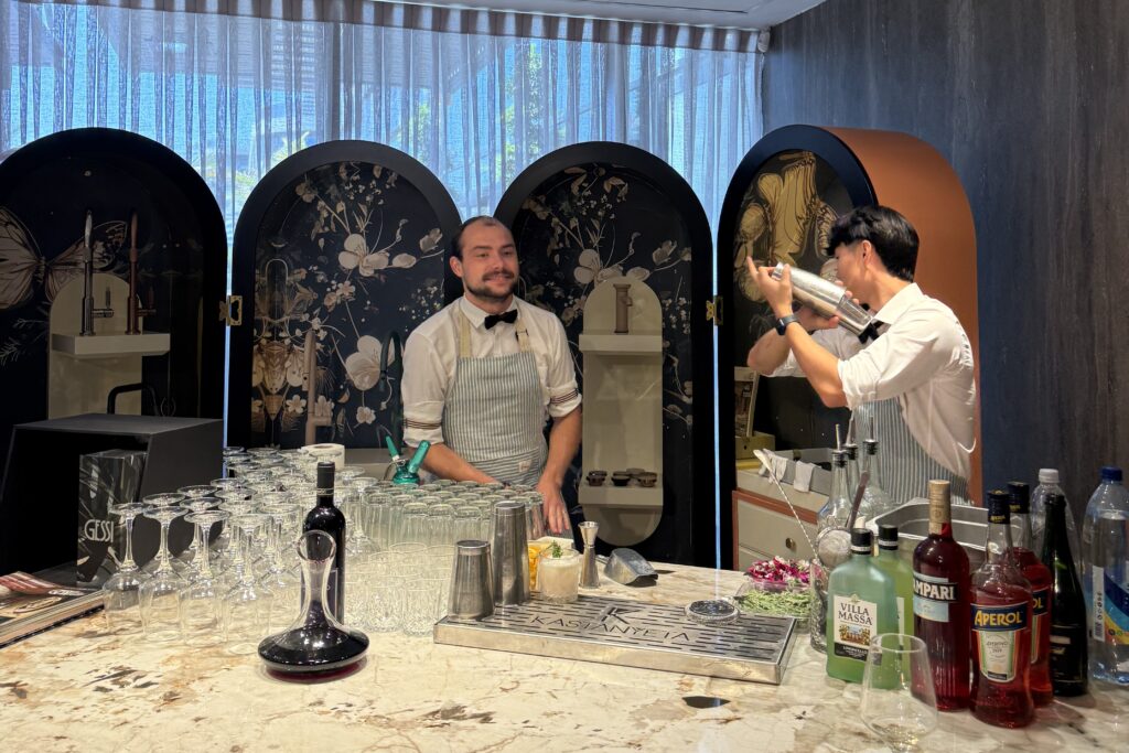 a barman shaking a cocktail and another smiling next to him